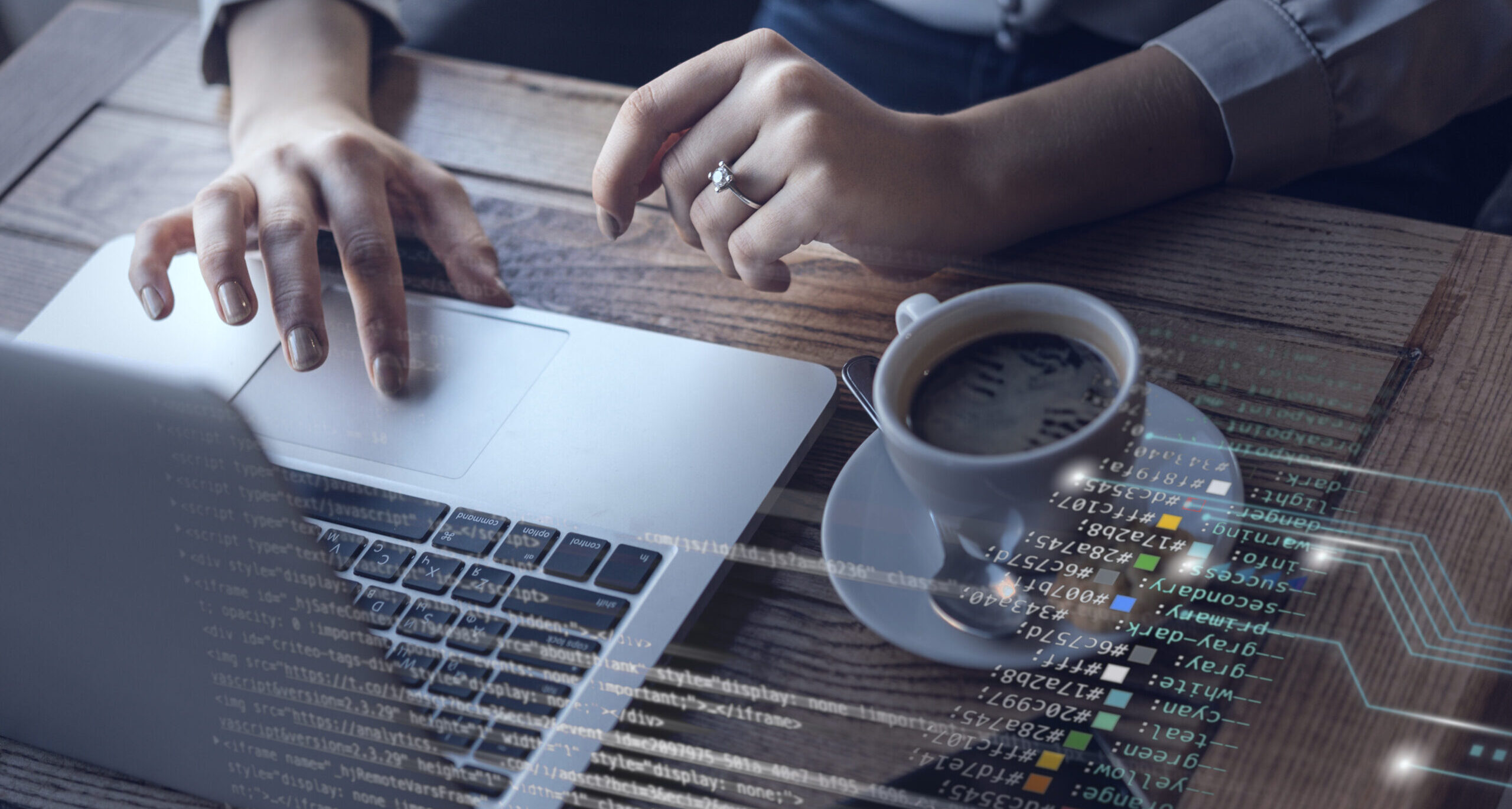Aparece una mesa, donde hay un ordenador, un cafe, un móvil y se ve como dos manos de mujer escriben en el teclado del ordenador.